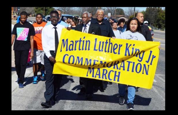 Residents carry the Martin Luther King Jr. banner as they march along FM 116
with members of Bible way Missionary Baptist Church Monday.