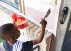 COURTESY PHOTO - Little Mister Rabbit Fest Azaire Barrett, 6, gets busy painting near the front door of My Brother’s House, the food pantry of the Holy Family Catholic Church, on Saturday. It took 15 volunteers more than 10 hours to paint the facility.