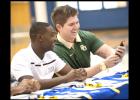 CCLP/DAVID MORRIS - Shamad Lomax, left, and J.P. Urquidez react to a message on Urquidez’s phone during Wednesday’s signing ceremony. Lomax and Urquidez signed to play for the highest echelon in college football with New Mexico State and Baylor, respectively.